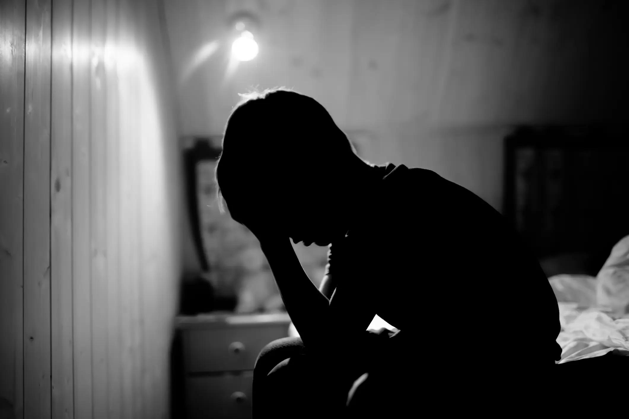 Silhouette of person sitting in dimly lit room.
